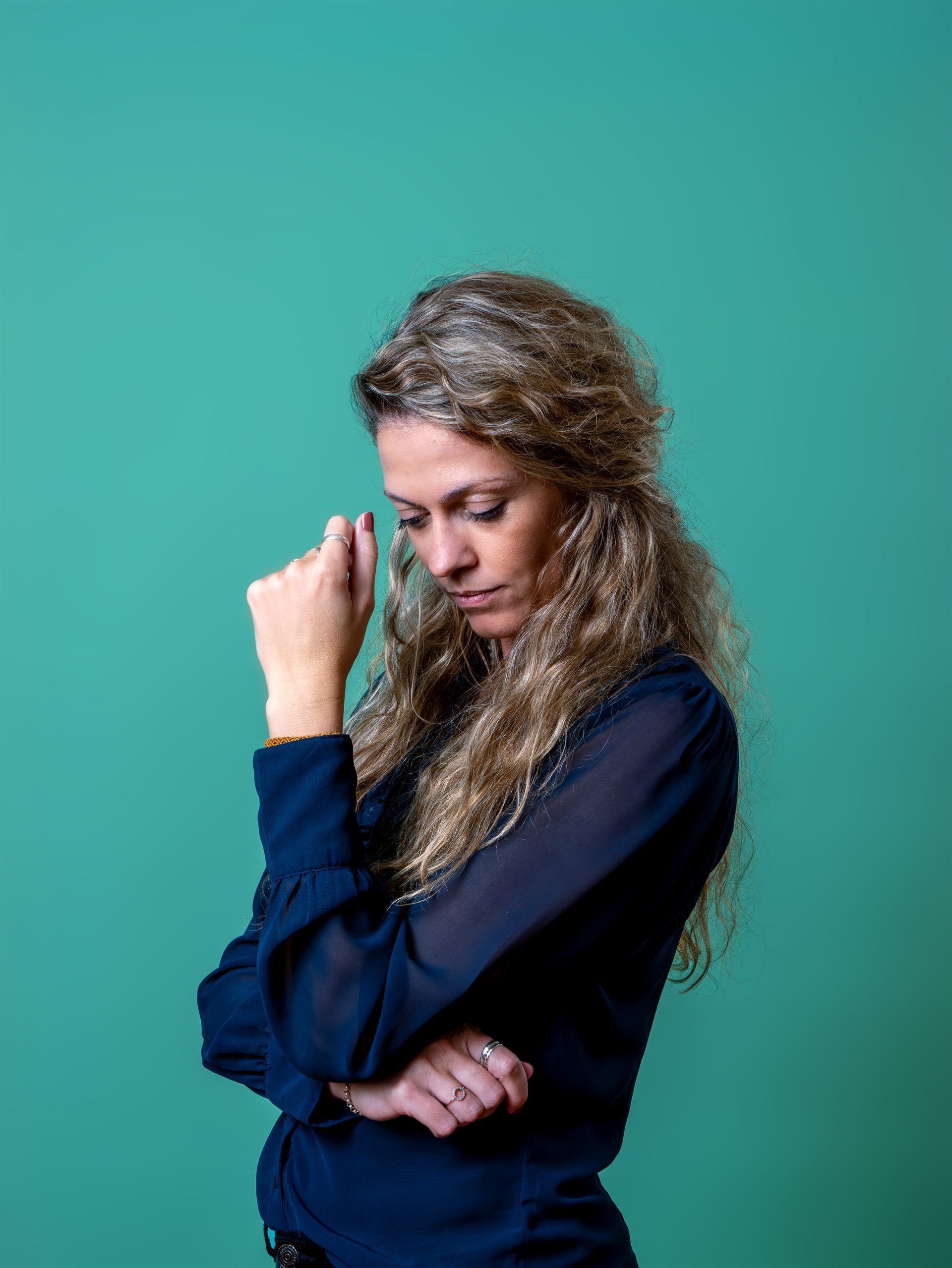 Creatief portret van een vrouw in een donkerblauwe blouse tegen een turquoise achtergrond.